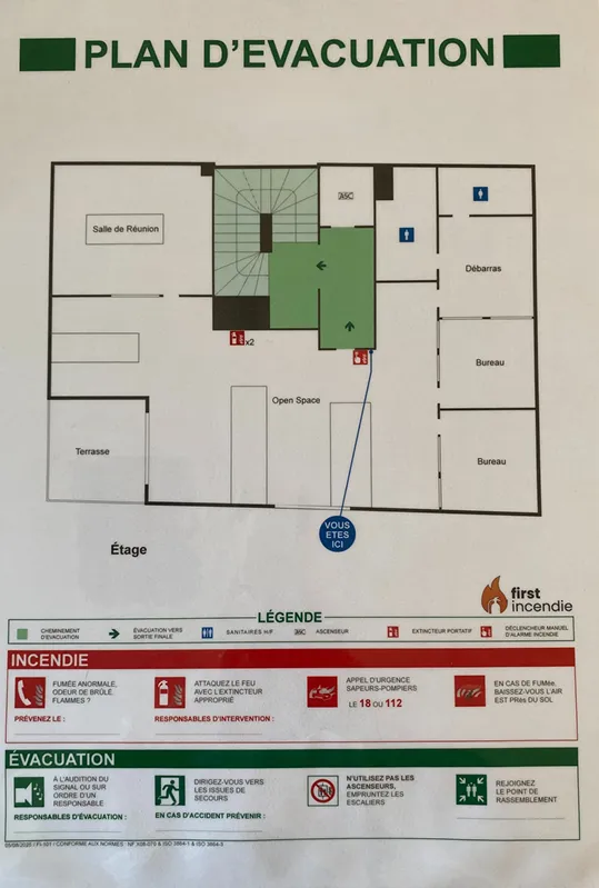 Plan d'évacuation d'un étage de bureaux, avec le cheminement en vert, le point Vous êtes ici, les extincteurs, et en bas les consignes Incendie et Évacuation